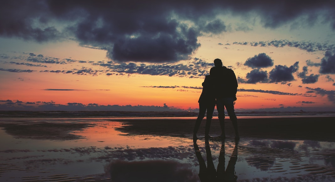 couple stares out toward the ocean at sunset