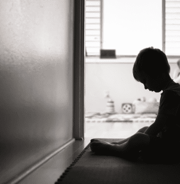 black and white image of young child handing head in a hallway