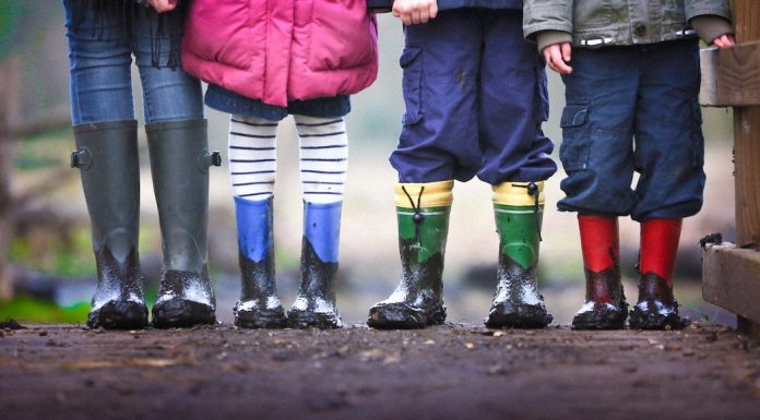 4 kids with rainboots on in mud