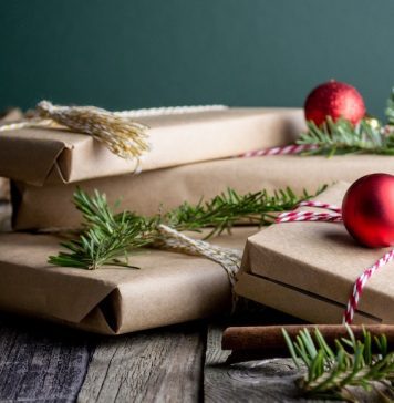 Group of presents wrapped in kraft paper, with ornaments and leaves around gifts