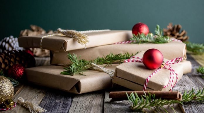 Group of presents wrapped in kraft paper, with ornaments and leaves around gifts