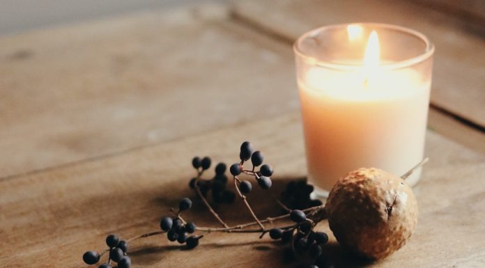 A lit candle next to nuts and dried berries on a wooden table
