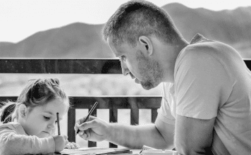 Father sitting at the table with his young child to color and talk