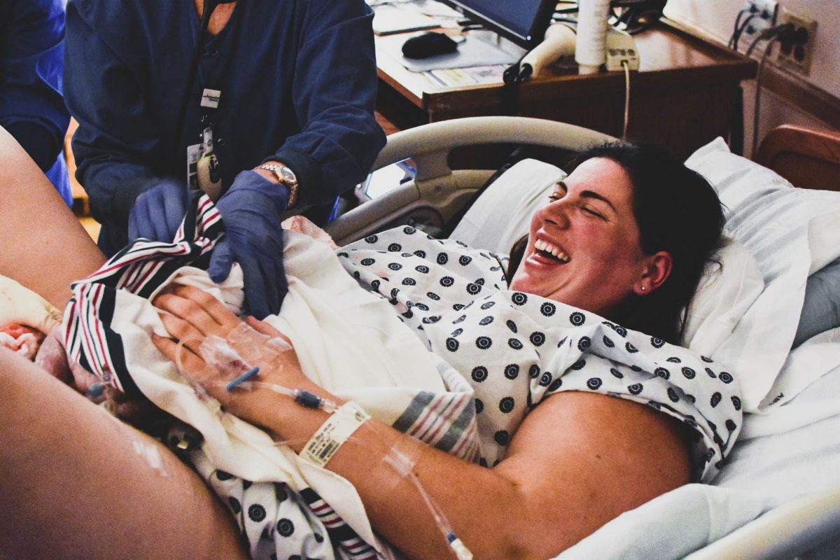 A mother who has just delivered her baby looks down in happy surprise