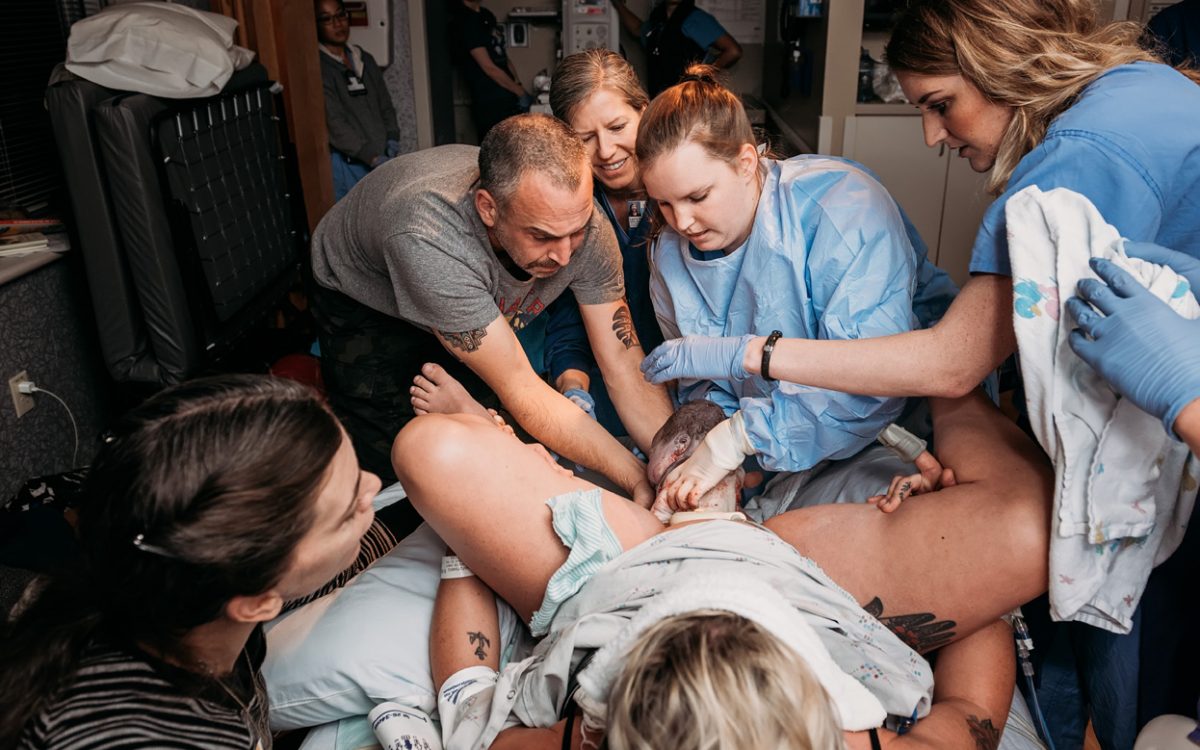 A birth team, including the baby's dad, helps deliver his child from Jen Berryman Photography