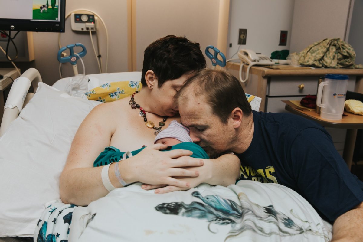 A mother and father cuddle their newborn baby together by Meg Ross Photography