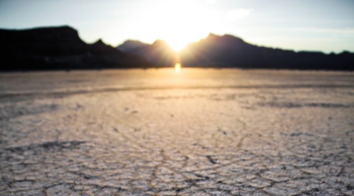 Dry desert with sun behind mountains