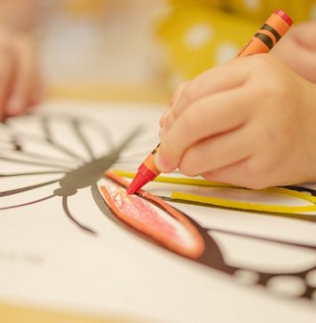 Child coloring butterfly with crayon