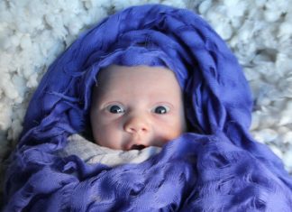newborn baby wrapped in indigo fabric with look of surprise on their face