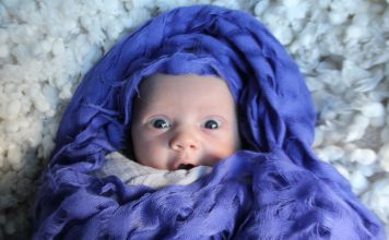 newborn baby wrapped in indigo fabric with look of surprise on their face