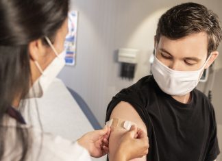 Medical provider places a bandage on patient's arm after innoculation