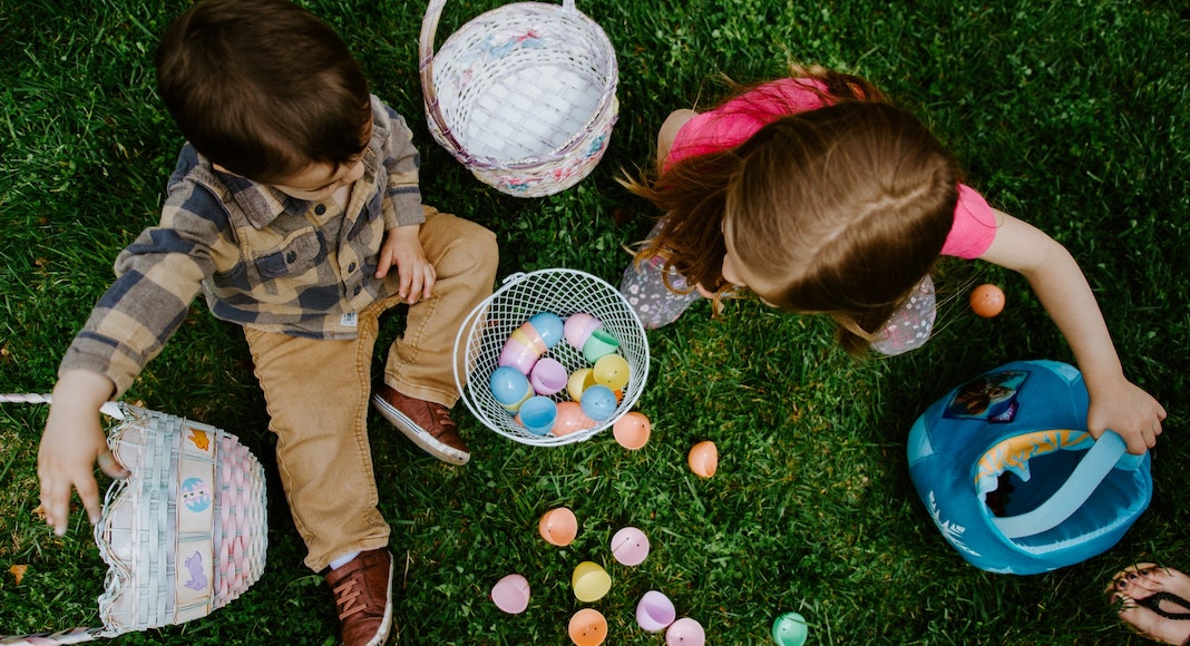 Two kids collect Easter eggs on the grass