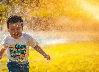 Kid running through sprinkler on lawn