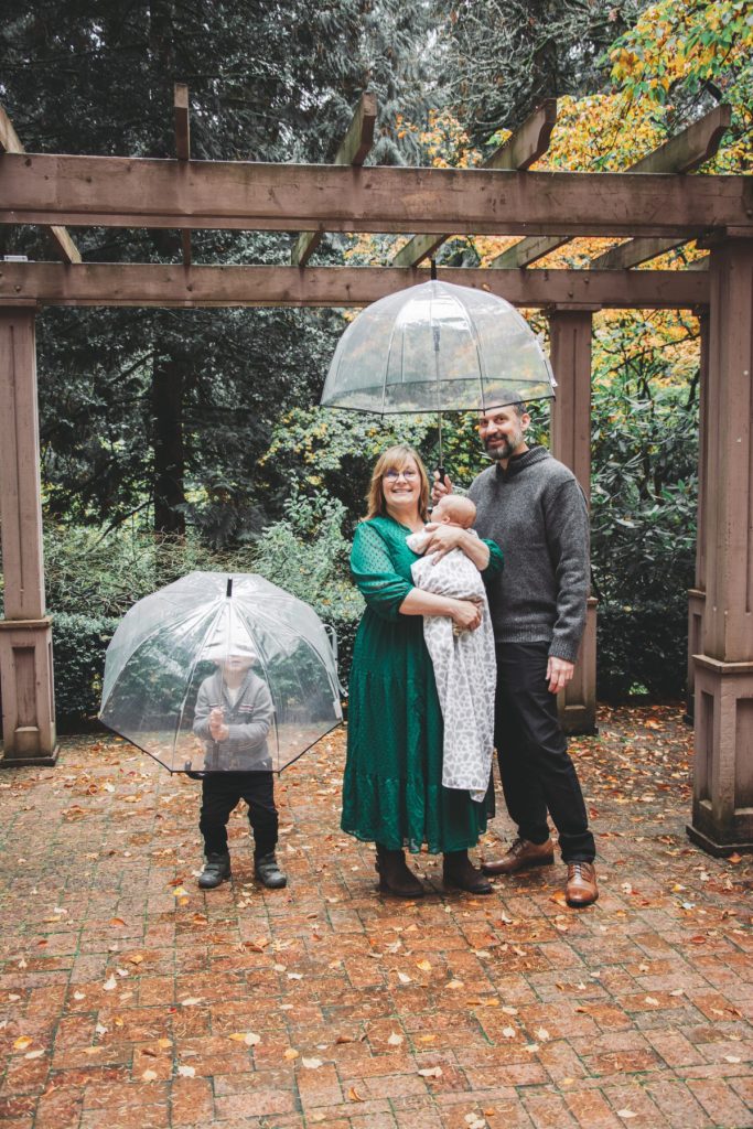Mom, Dad, preschooler brother and baby under umbrellas at Leach Botanical Garden in the fall