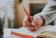 Person journaling holding an orange pen