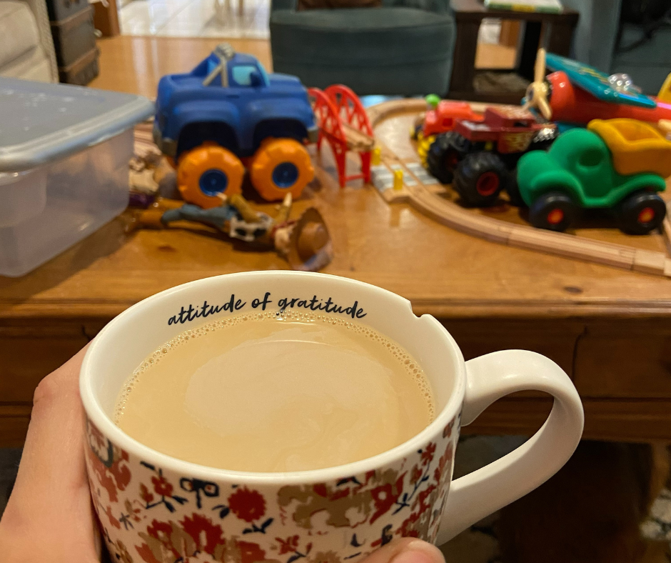 chipped coffee cup, children's toys on table, 'attitude of gratitude' on cup