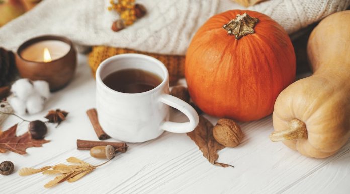 Cozy autumn scene with coffee, gourds, dried leaves on a white table