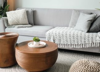 A clean and tidy living room couch sits in a room, with two shining coffee tables in front of it.