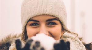 Girl smiling holding snow in front of her face
