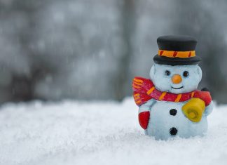 A snowman figurine sits in a pile of snow.