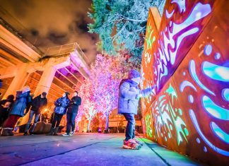A kid stands in front of light display at Portland Winter Light Festival