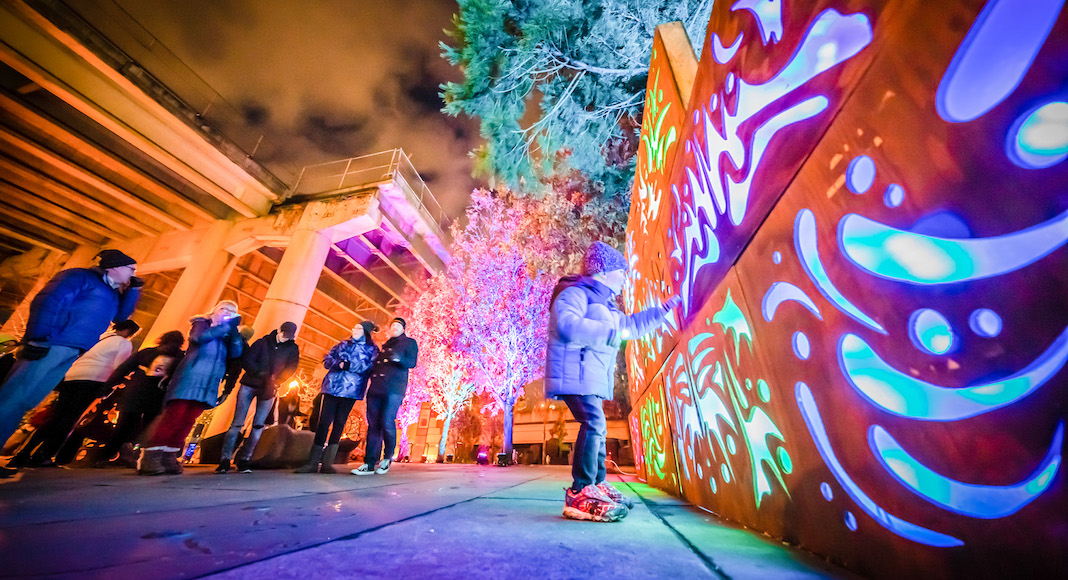 A kid stands in front of light display at Portland Winter Light Festival