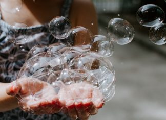 A kid holds a handful of bubbles on a summer day.