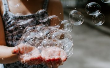 A kid holds a handful of bubbles on a summer day.