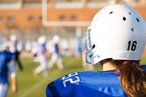 Image of girl in tackle football uniform, waiting to go into game