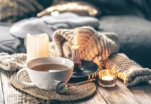 Image of hygge-inspired cozy tea setting with candles and blankets.