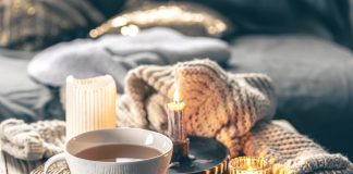 Image of hygge-inspired cozy tea setting with candles and blankets.