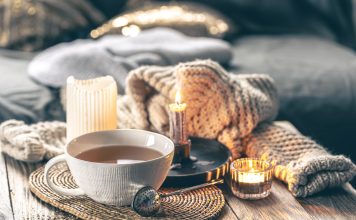 Image of hygge-inspired cozy tea setting with candles and blankets.