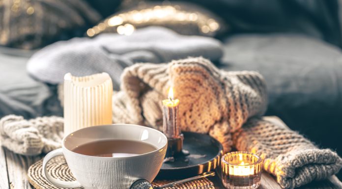 Image of hygge-inspired cozy tea setting with candles and blankets.