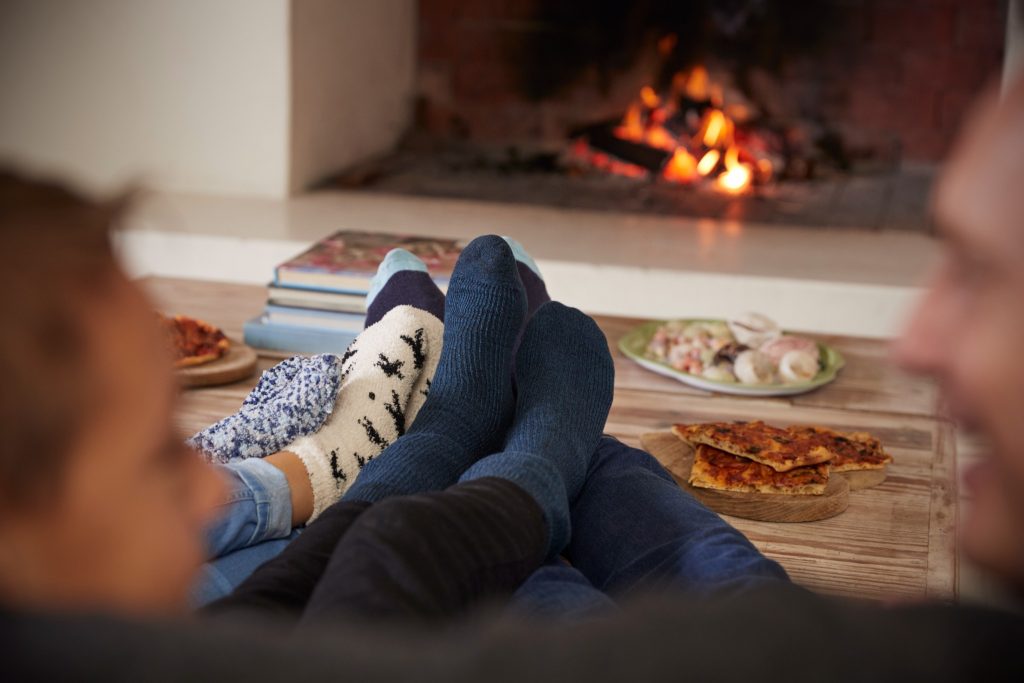 Image of people in cozy socks warming their feet by the fireplace.